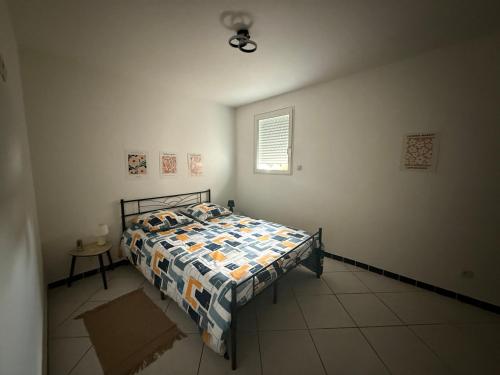 a bedroom with a bed with a quilt on it at Petit nid chaleureux in Mimizan