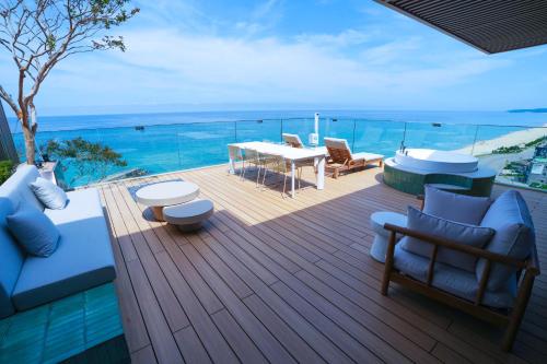 a deck with a table and chairs and the ocean at 클리프비치 in Sangun-ni