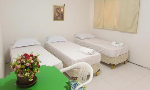 a room with two beds and a table with a plant at Pousada Sitio Costa Verde in Ubajara