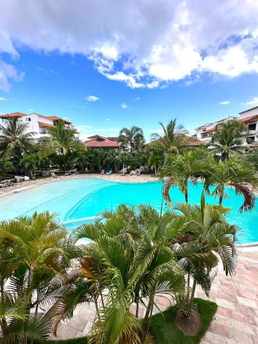 a large swimming pool with palm trees in the foreground at Paraiso Destiny E2 in Bayahibe