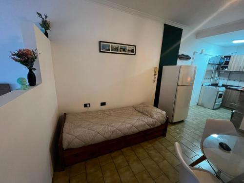 a small bedroom with a bed and a refrigerator at Departamento Las Golondrinas in Estación Coronel Maldonado