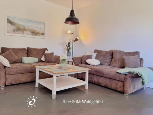 a living room with a brown couch and a table at Nordprinz mit Sauna und Whirlpool in Geestland