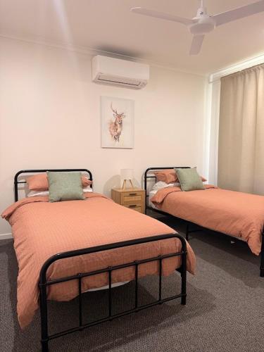 a bedroom with two beds with orange comforters at Valley View House in Gympie
