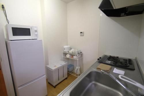 a kitchen with a sink and a microwave on top of a refrigerator at オンブラージュ704号室-無料駐車場付き-繁華街まで徒歩圏内-南向きで明るいワンルーム in Kumamoto