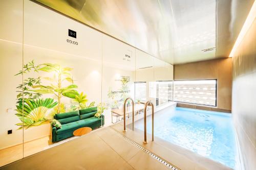 a bathroom with a pool with a couch and plants at 대구 이스턴호텔 라이온즈파크점 in Daegu