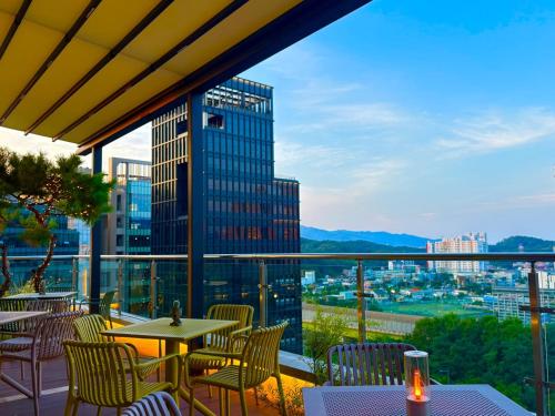 a balcony with tables and chairs and a view of a city at 대구 이스턴호텔 라이온즈파크점 in Daegu