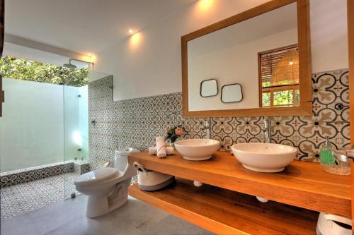 a bathroom with two sinks and a toilet and a mirror at Porto Alegre Villas in Punta Uva
