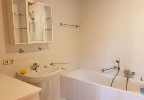 a white bathroom with a sink and a bath tub at Ruhige Wohnung im Grünen Lichtenwald in Thomashardt