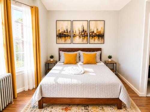a bedroom with a bed with three paintings on the wall at Journal Sq PATH - Private Queen Room - Private Bath - Shared Kitchen - 15 Min to NYC in Jersey City