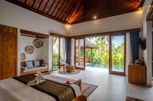 a bedroom in a villa with a bed and a patio at Dewi Kunti Villa in Tegalalang