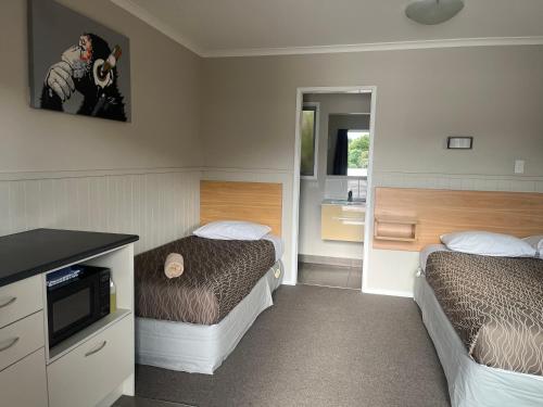 a hotel room with two beds and a bathroom at Stratford Motel & Holiday Park in Stratford