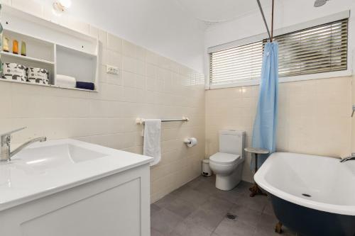 a bathroom with a sink and a toilet and a tub at Stockton Coastal Escape in Stockton