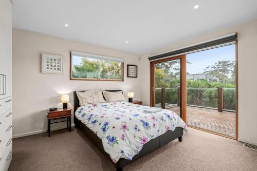 a bedroom with a bed and a large window at 9 Doors From Front Beach in Point Lonsdale