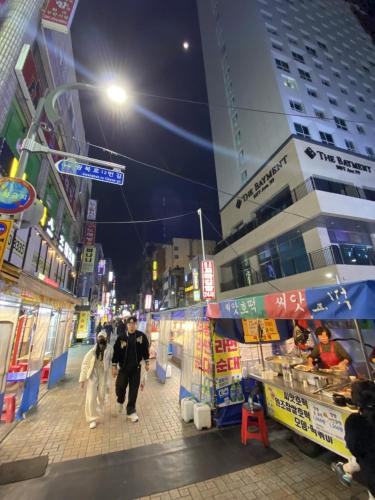a couple of people walking down a street at night at The Bayment Stay in Busan