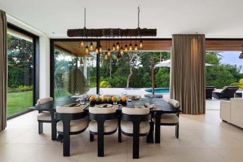 a dining room with a black table and chairs at Mandalore Villas Ubud - Adults Only in Ubud