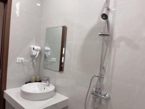 a white bathroom with a sink and a shower at TRƯỜNG THỊNH Hotel in Hòn Tru
