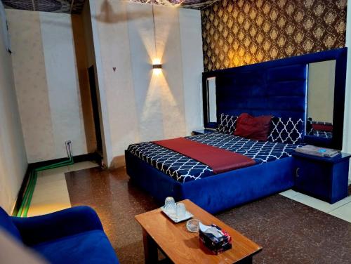 a bedroom with a blue bed and a table at Hotel Moon Light view in Lahore