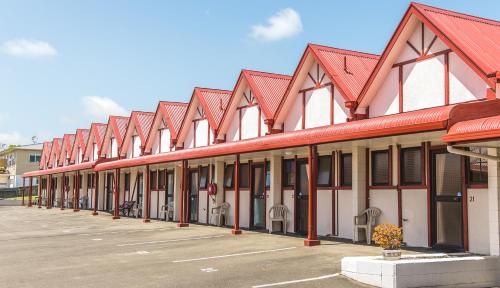 a row of buildings with red roofs in a parking lot at Burwood Motel in Whanganui