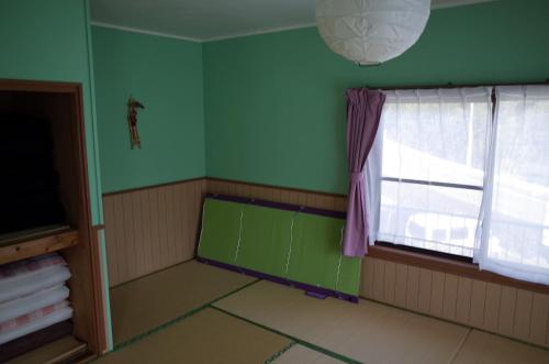 a room with a window and a green wall at Kashi Besso Takachiho in Takachiho