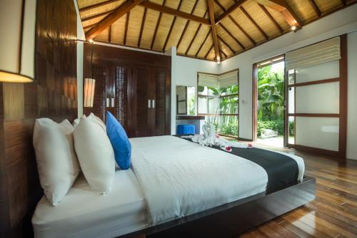 a bedroom with a large bed with blue and white pillows at Arama Riverside in Legian