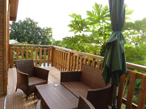 a patio with chairs and an umbrella on a deck at Le Bougainvillier Blanc in Pointe-Noire