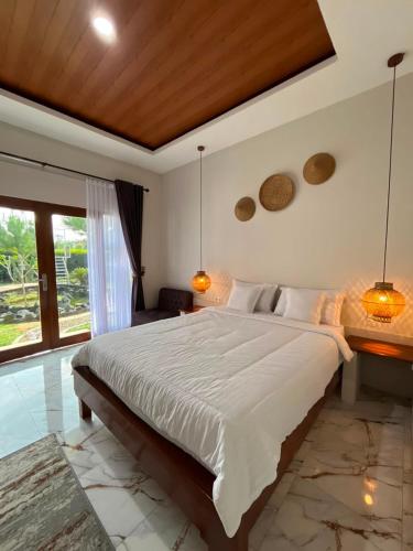 a bedroom with a large white bed with two lamps at Villa Bumi Detani in Selabintana