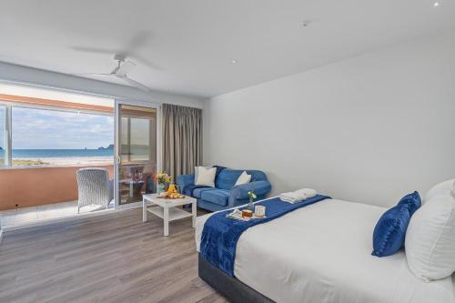 a bedroom with a bed and a view of the ocean at Seaview Studio Apartment - Beachfront with Heated Pool in Whitianga