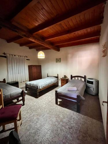 a bedroom with two beds and a wooden ceiling at Departamento Ayllu IV in Tilcara