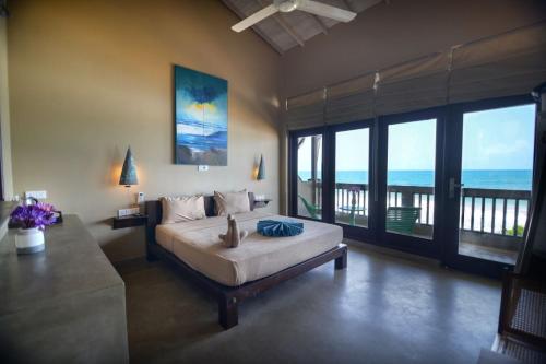 a bedroom with a bed with a view of the ocean at At Ease Beach Hotel in Hikkaduwa