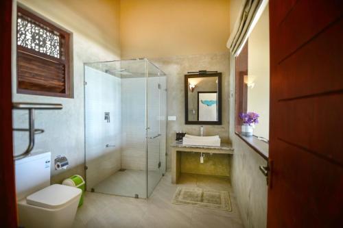 a bathroom with a shower and a toilet and a sink at At Ease Beach Hotel in Hikkaduwa