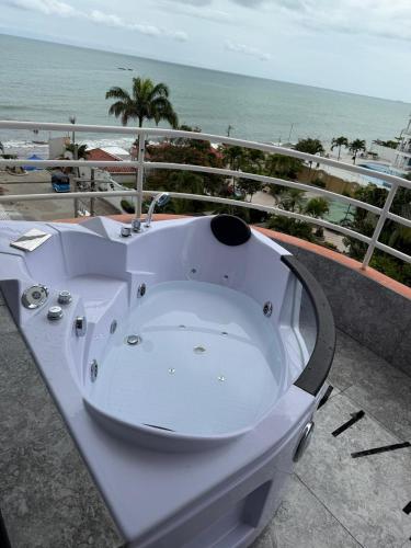 a white bath tub sitting on a balcony overlooking the ocean at Departamento moderno con jacuzzi privado - Porto Vitoria in Tonsupa
