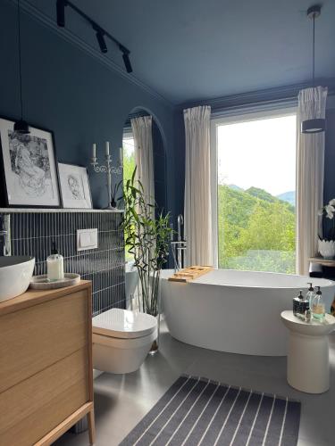 a bathroom with a tub and a toilet and a window at Cabana207 - Private Mountain Cabin with Hot Tub in Bulz