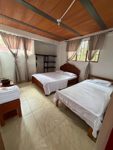 a bedroom with two beds and a table and windows at Finca Agroturística La pradera in Acacías