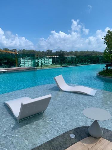 two white chairs and tables on a swimming pool at The Title Serenity Naiyang in Ban Bo Han