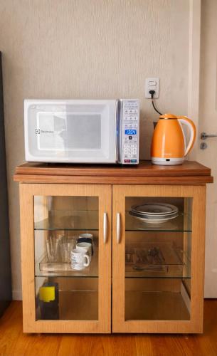 a microwave sitting on top of a wooden cabinet at Quarto Privativo Próximo à BR in São José