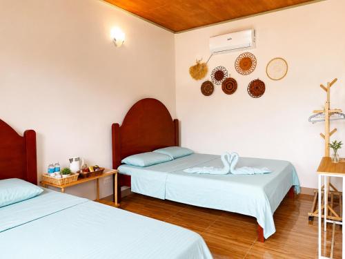 two beds in a room with white walls and wooden floors at The Shuim Dive Resort Moalboal in Moalboal