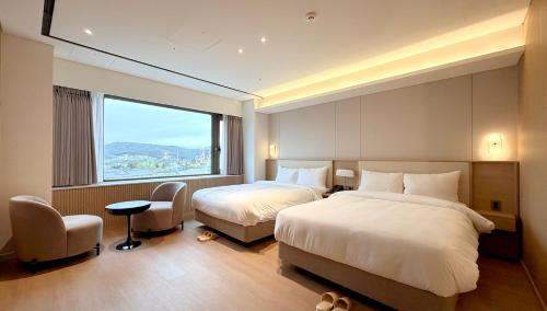a hotel room with two beds and a window at The K Hotel Gyeongju in Gyeongju