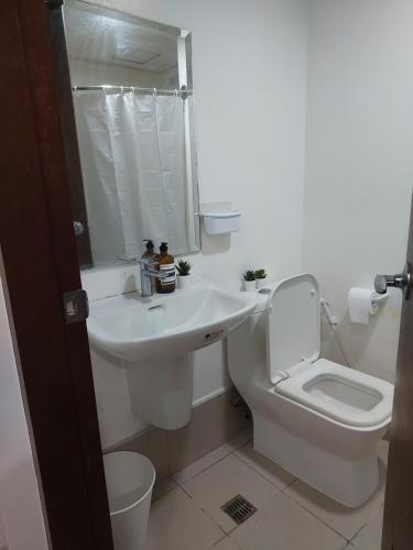 a white bathroom with a sink and a toilet at Siena Tower - Gian's Nook in Manila