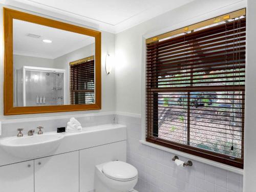 a bathroom with a toilet and a sink and a window at Vilamoura in Pokolbin