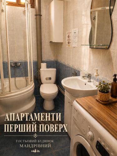 a bathroom with a toilet and a sink and a washing machine at Guest House Mandrivnyi Rooms&Apartments in Yasinya