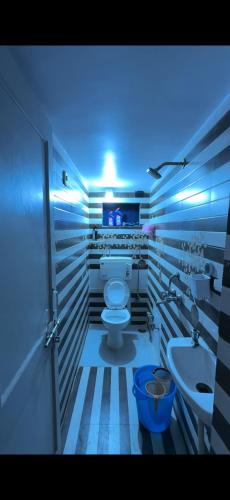 a bathroom with a toilet and a sink and a blue light at Ajay Niwas in Udaipur