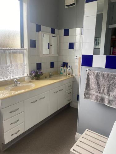 a white bathroom with two sinks and a window at Arthurstown Rd Riverview House in Ruatapu