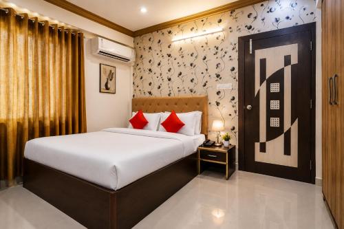 a bedroom with a bed with white sheets and red pillows at Hotel Amrapali Udaipur in Udaipur