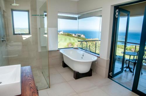 a bathroom with a tub and a view of the ocean at Hippo House in Knysna