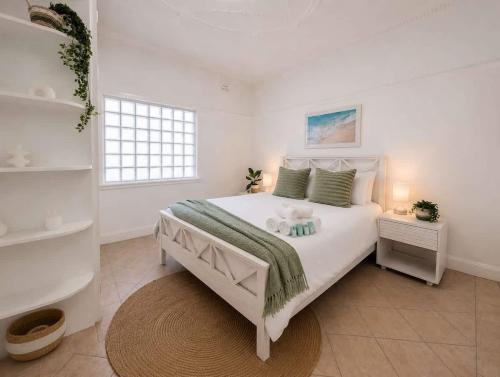 a bedroom with a white bed with a teddy bear on it at Cozy Loft Beach House in Wollongong