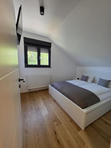 a bedroom with a white bed and a window at Luni Stay - Jacuzzi, Sauna & Nature Escape in Jastrebarsko