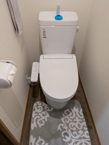 a bathroom with a toilet with a blue object on top of it at Kumanokodo KURA in Shingū