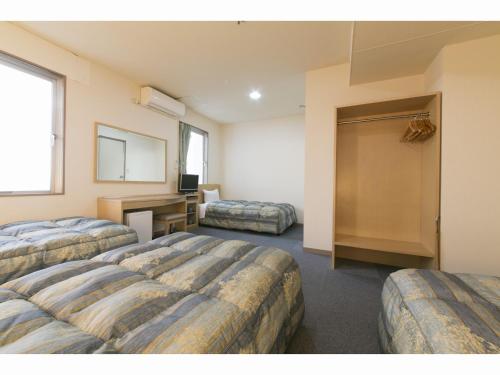 a hotel room with two beds and a desk at Business Hotel Okada Toyohashi in Toyohashi