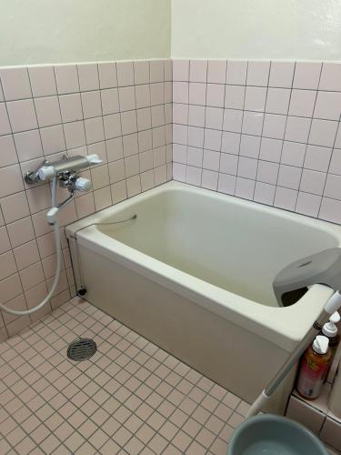a bath tub in a bathroom with a tiled floor at ゲストハウスぬっく in Tanabe