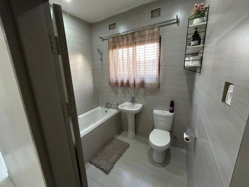 a bathroom with a toilet and a tub and a sink at Serenity Haven in Chongwe